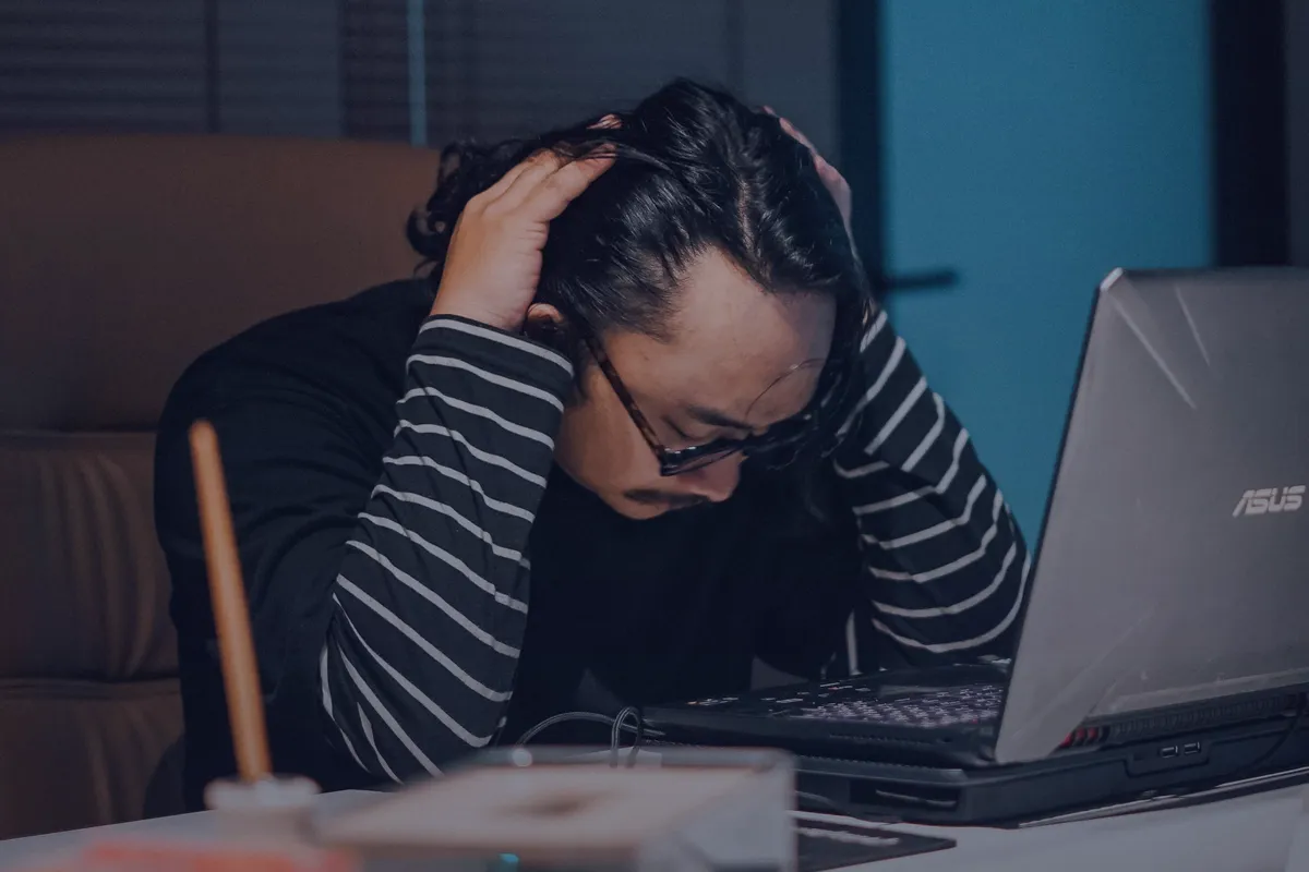 A business owner at a laptop late at night with both hands in his hair